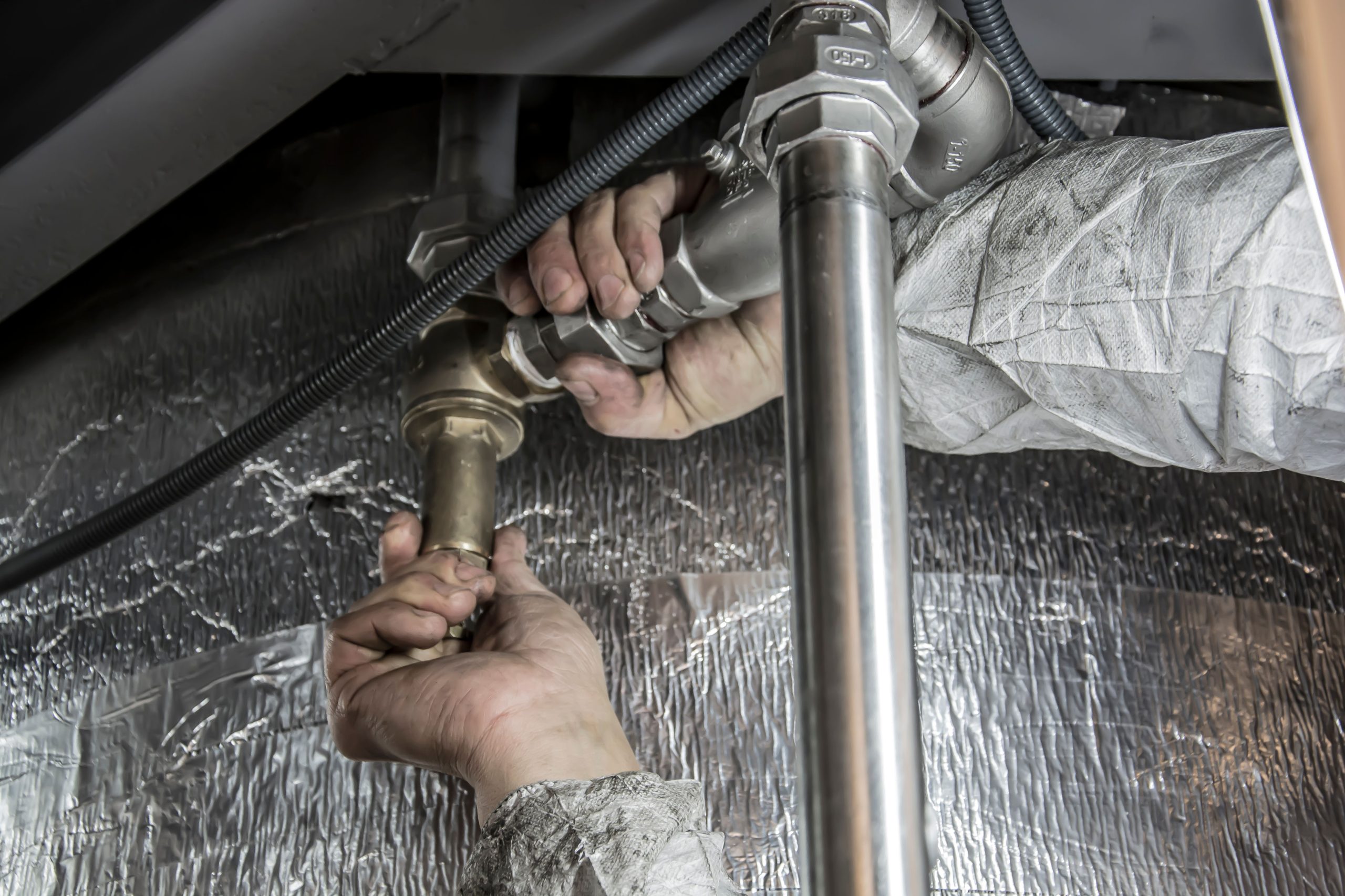 Mains de plombier installant tuyaux acier